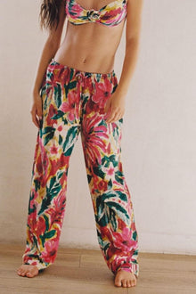 Wide-leg pants with red, pink, yellow, and green floral print and drawstring waist.