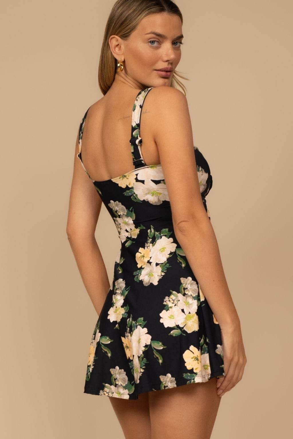 Black sleeveless dress with cream and yellow floral print, thin straps, and fit-and-flare silhouette.