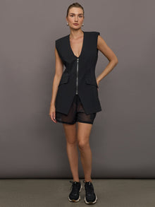 Model wears black Odyssey Vest with a silver front zip, pockets and a v-neckline.