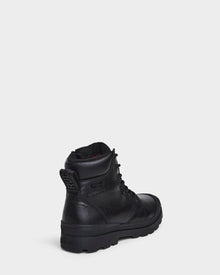 The Rudsak ARTUR - M223501 Black men's ankle boot, crafted from weather-treated leather, is shown angled on a white background, featuring a rugged sole and embossed branding for stylish durability.