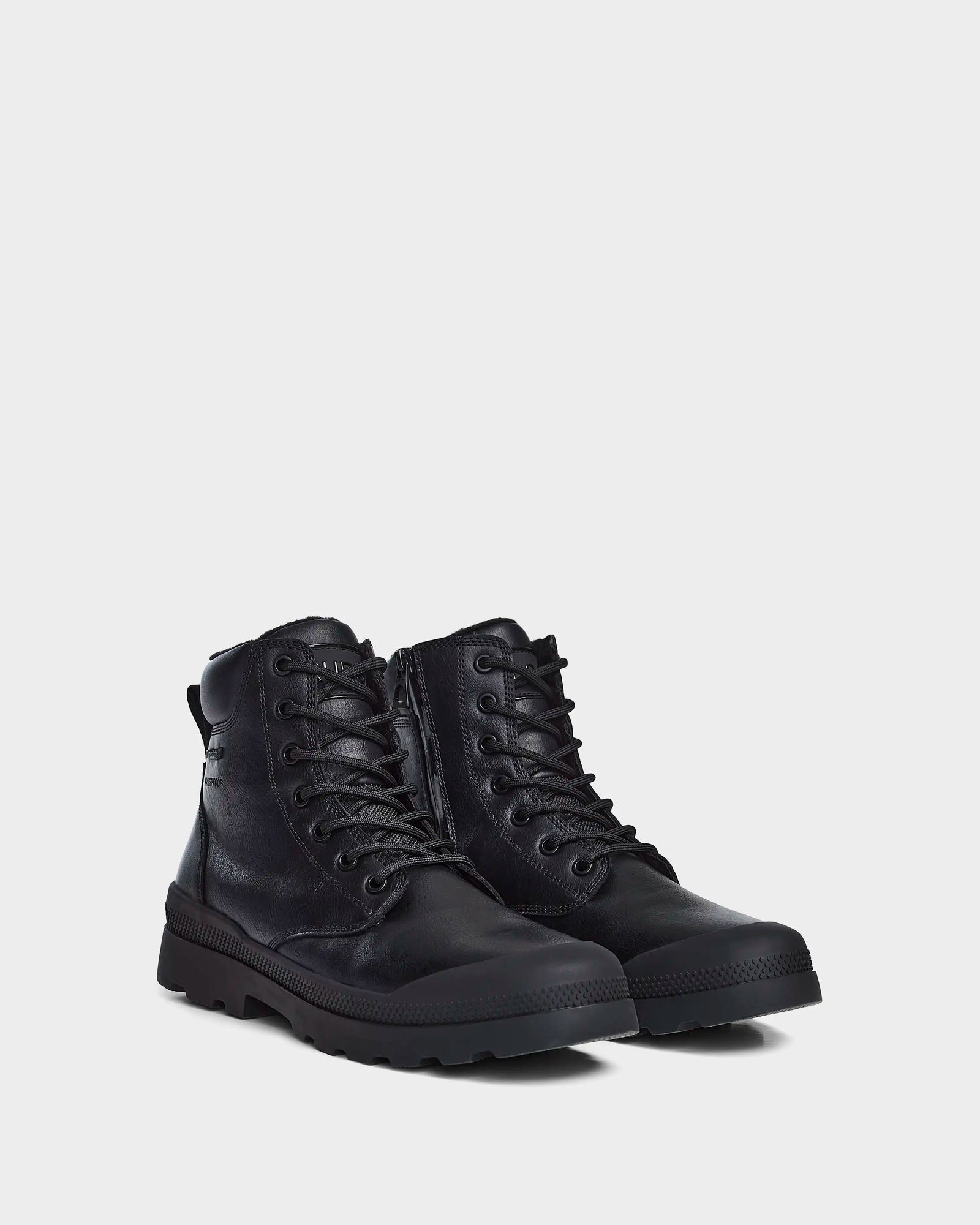 The ARTUR - M223501 Black men's boots by Rudsak feature stylish black weather-treated leather, rugged soles, side zippers, and padded collars, shown against a plain light grey background.