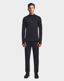 A man faces forward wearing Rudsak’s WARREN - 6523502 Black fitted stretch zip-front mock neck top and matching black pants with black shoes, set against a plain light gray background.