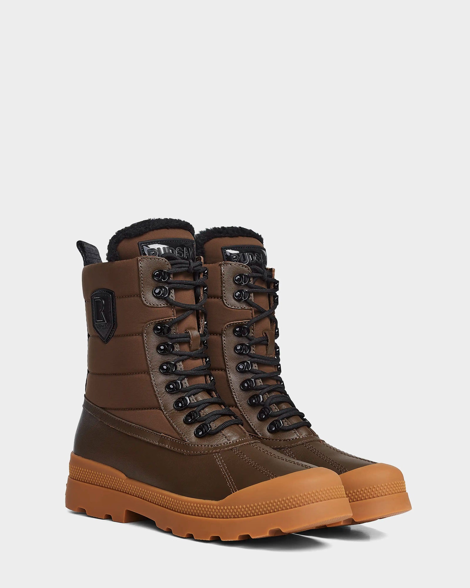 The Rudsak REAGAN - 6222500 Army mens winter boots feature brown uppers, black laces, padded black collars and accents, plus thick light brown treaded rubber soles, shown on a white background.