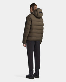 A woman wearing the Rudsak DEMIAN M - M123507 Light Olive hooded down puffer, crafted from sustainable recycled fabric.