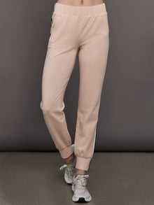 Model wears baby pink jogger pants with side stripes, elastic waistband, and cuffed ankles.




