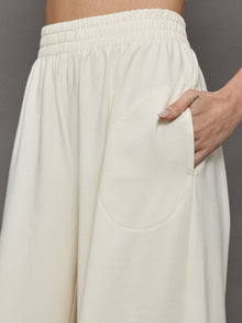 Model wears a pair of oversized wide leg cream colored sweatpants. 