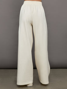 Model wears a pair of oversized wide leg cream colored sweatpants. 