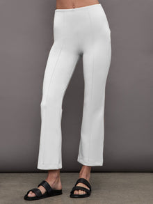 Model wearing cropped white flare pants with pintuck detail, front view.