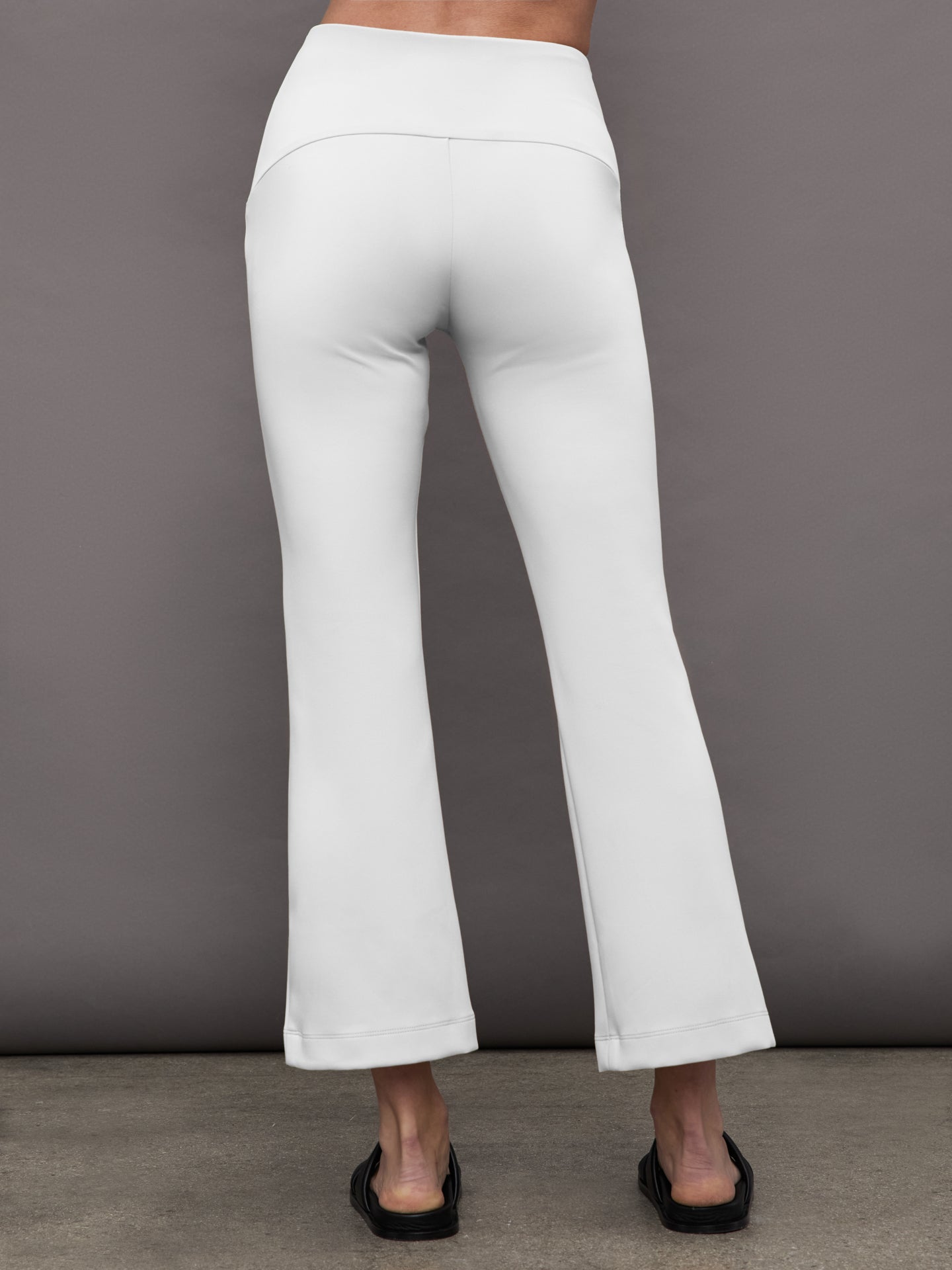 Back view of white flare pants with high waistband and flare hem.