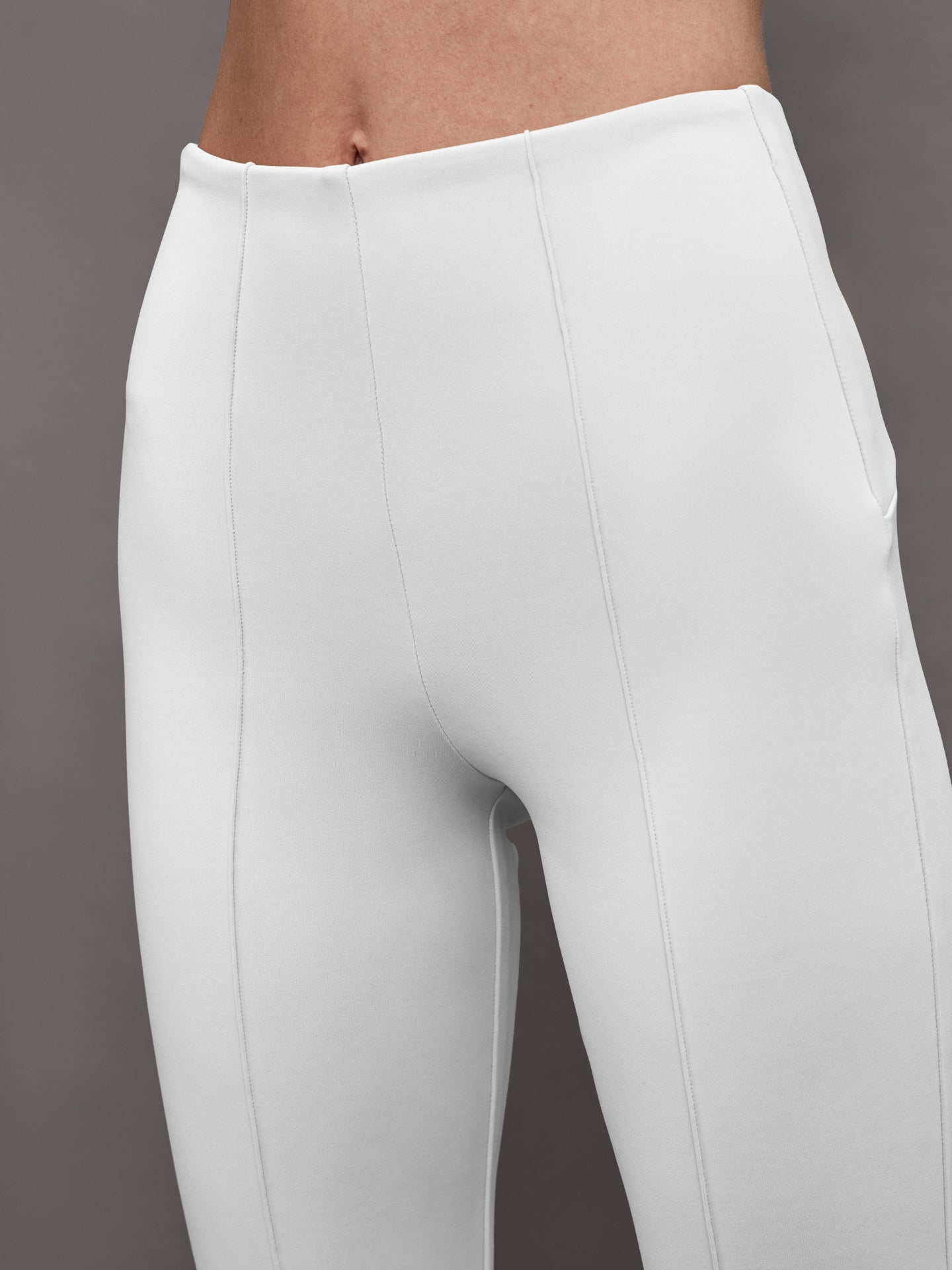 Close-up of white flare pants waistband and front seam detail.