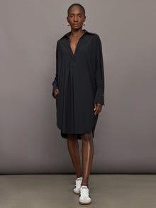 Model wearing black oversized shirt dress with wide cuffs, front view.