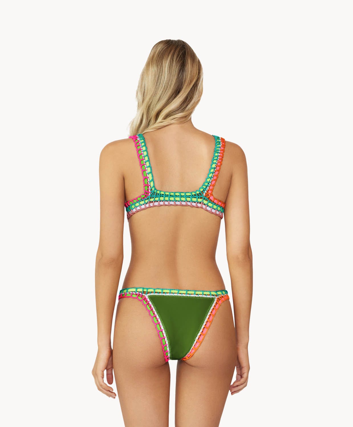 A blonde woman wearing an olive green bikini facing towards a white wall.