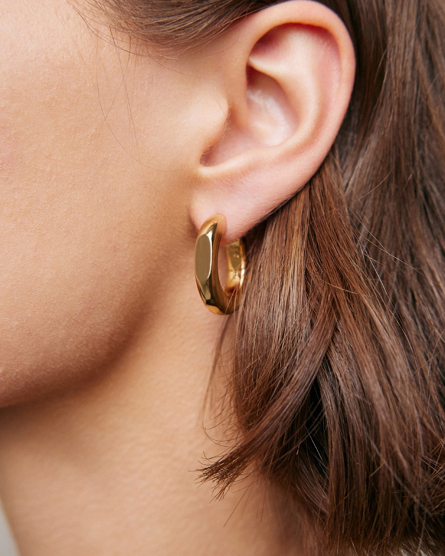 Model wearing huggie earring. 