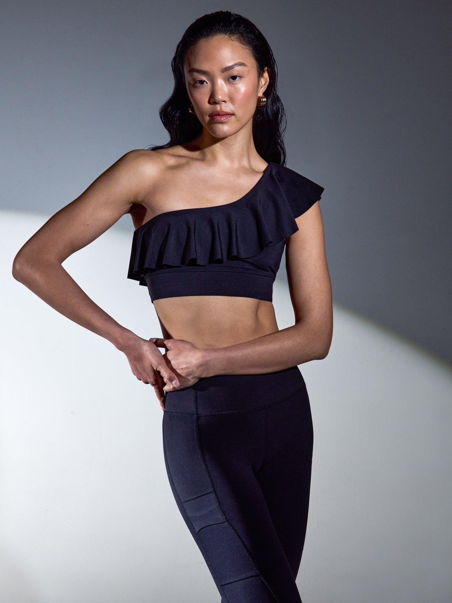 Model wearing the Ruffle One Shoulder Bra in Diamond Compression Black under studio lighting, front view