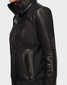 Someone models the Rudsak PRESLEY - CA EN 8119029 BLACK lamb leather biker jacket, featuring quilted shoulders and sleeves plus a zippered pocket, viewed from the side against a plain light background.