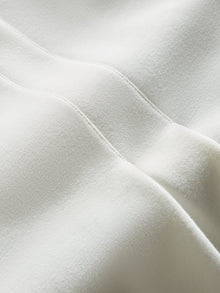 Model wears the white double-breasted blazer in Scuba, with a tailored fit, and a smooth, contoured finish.