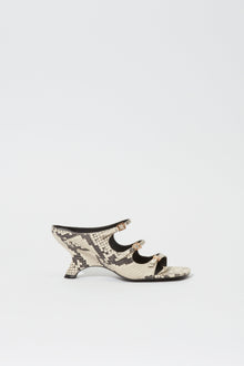 Cream and black snake print leather mule with buckle straps and curved heel, shown in profile.