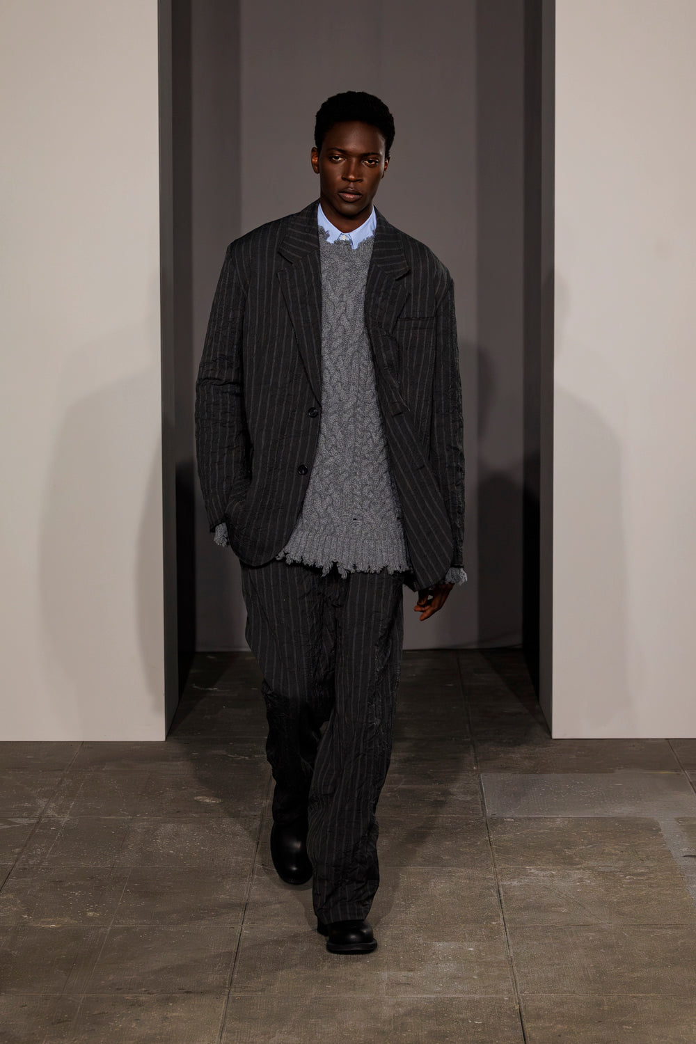 Charcoal pinstriped double pleat pants worn with matching blazer and gray sweater.