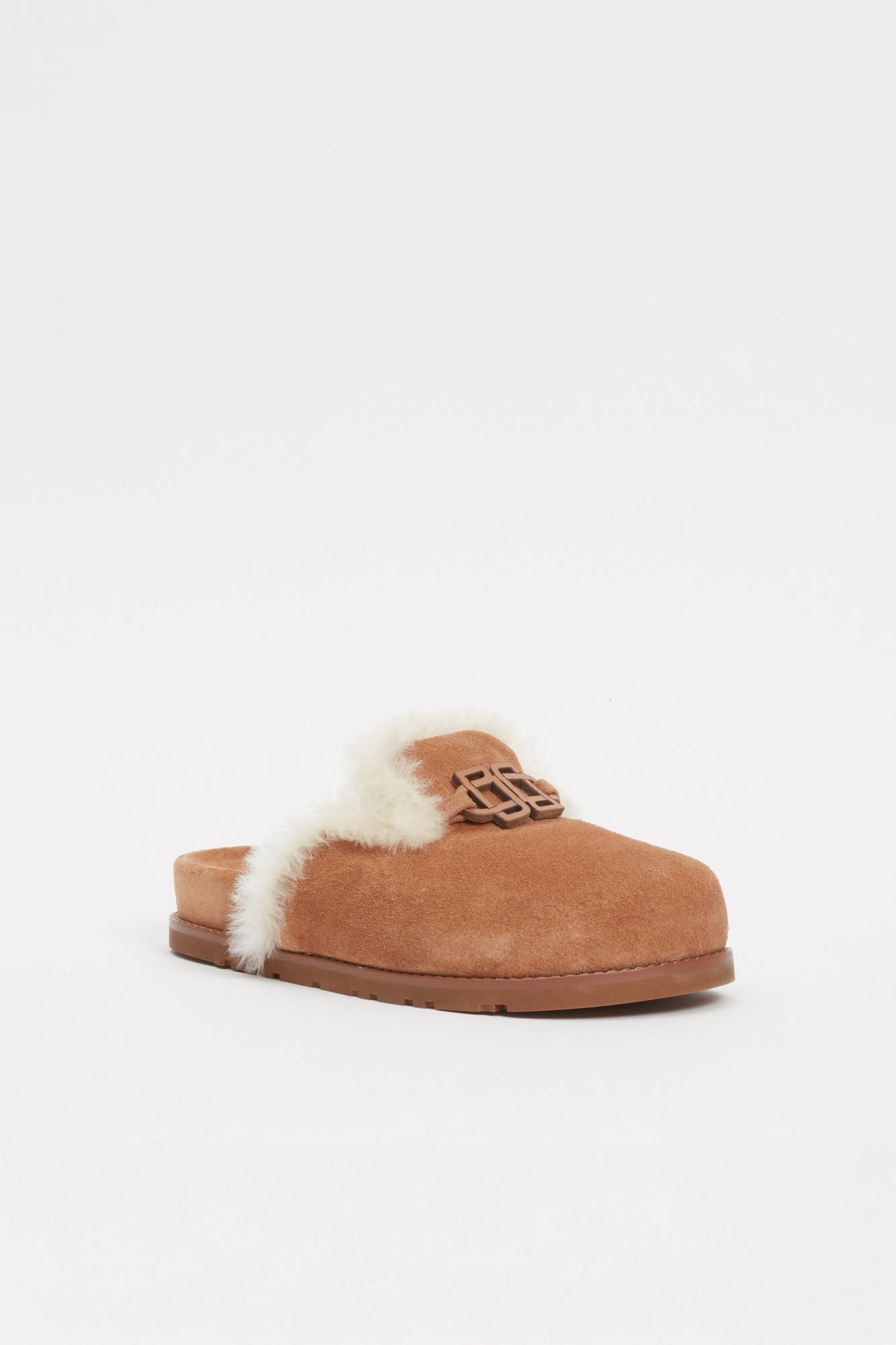 Tan suede slide with cream shearling lining and decorative buckle detail on upper.