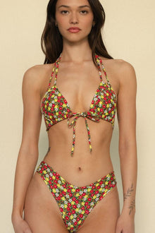 Woman wearing red, yellow, and white floral print bikini top with bow tie center and halter straps.