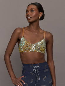 Model is wearing a paisley v neck sports bra with brown, white, and blue coloring. 
