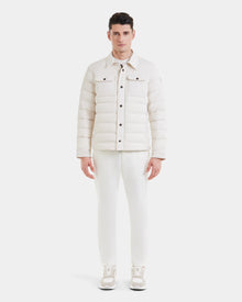A man faces forward against a plain white background, wearing the Rudsak AZIEL - M124521 Vanilla duck down jacket with matching white pants and sneakers.