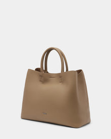 The Rudsak CATIRA L - 8325007 Almond is a spacious taupe women’s leather tote with two rounded handles, subtle stitching, and a small metallic logo on the front, displayed against a plain white background.