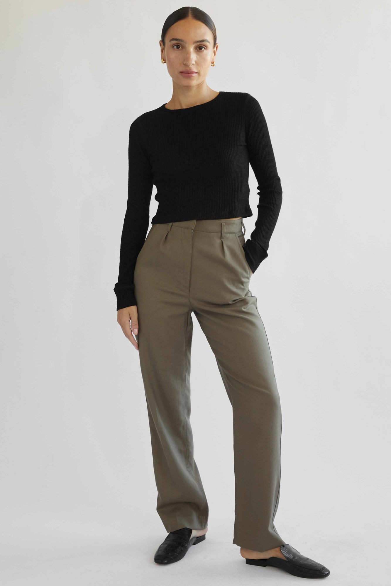 Woman wearing a black top and beige pants on a white background