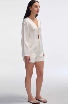 Woman wearing a white outfit on a plain background