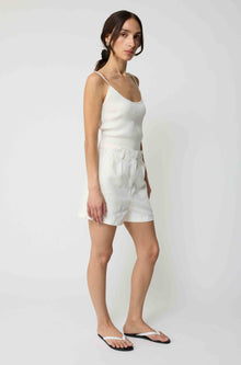 Woman wearing a white tank top and white linen shorts