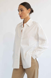 Woman wearing a white blouse and beige pants against a white background