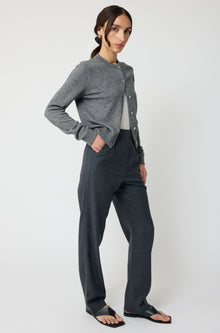 Woman wearing a gray cardigan and dark pants on a white background