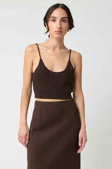 Woman wearing a brown ribbed tank top and skirt on a white background
