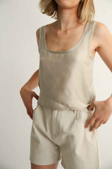 Person wearing a beige tank top and shorts set against a plain background