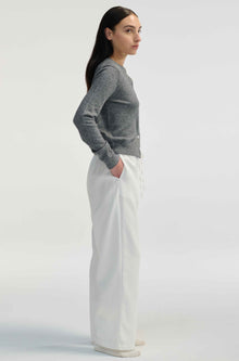 Woman wearing white linen pants on a light grey background