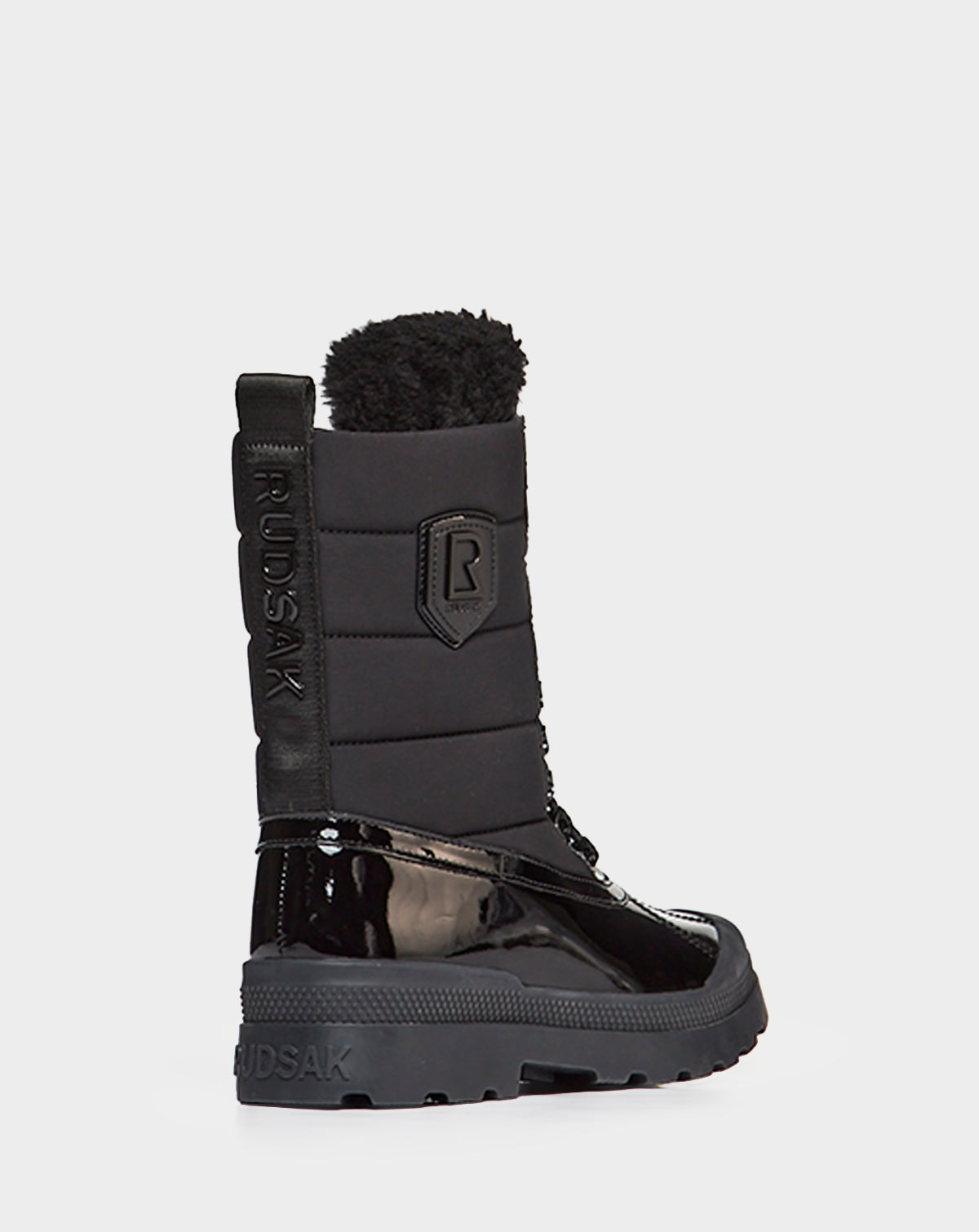 The Rudsak LEX - 8222501 BLACK is a women’s winter boot featuring a shiny patent leather lower, quilted upper, thick sole, side branding, pull tab, fuzzy top lining, and is stylishly waterproof for winter wear.