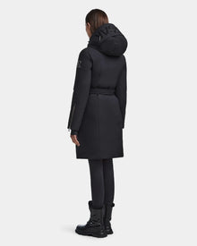 A person with wet, slicked-back hair models the RUDSAK MILENA - 8122536 BLACK women’s winter coat, paired with black leggings and boots, facing away from the camera against a plain light background.