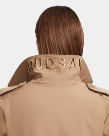 A person with straight brown hair is shown from behind, wearing the KINDA - 8124690 Camel womens trench coat by Rudsak, featuring RUDSAK EST. 1994 embroidered on its upturned collar.