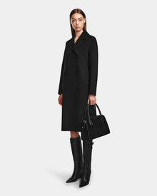 A woman in the LAYLAH - 8124699 Black knee-length double-breasted coat by Rudsak.
