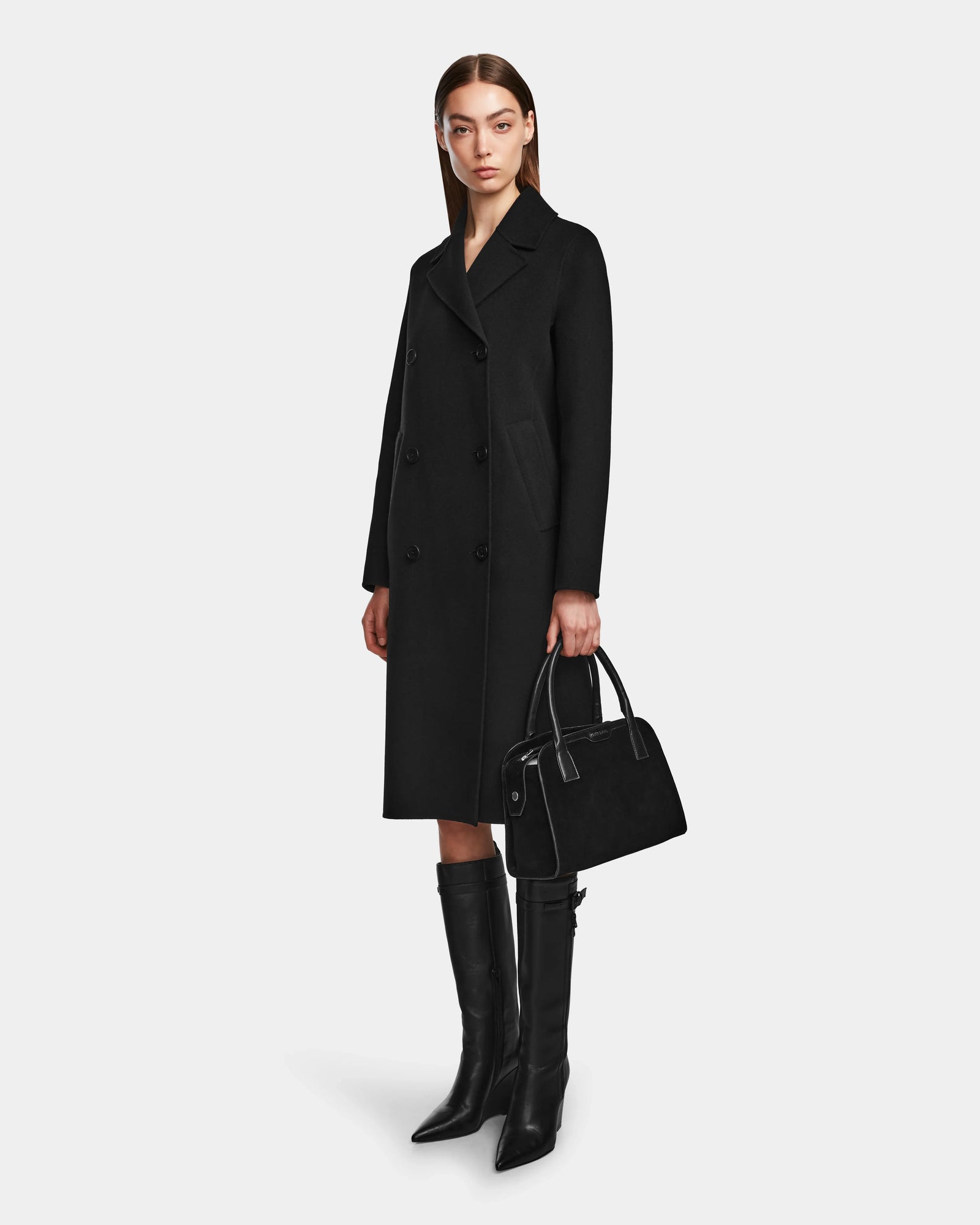 A woman in the LAYLAH - 8124699 Black knee-length double-breasted coat by Rudsak.