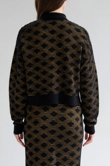 Full back view of a model wearing the Amelie Polo sweater in golden black.