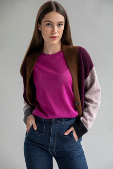 A woman wearing a fuschia colored short sleeve sweater tee made from baby alpaca silk paired with a color block cardigan in aubergine multi color.