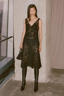 Black sequin and lace sleeveless midi dress with V-neckline worn with black boots.