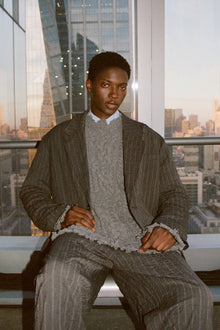 Charcoal pinstriped double pleat pants with distressed knee details worn with matching blazer.