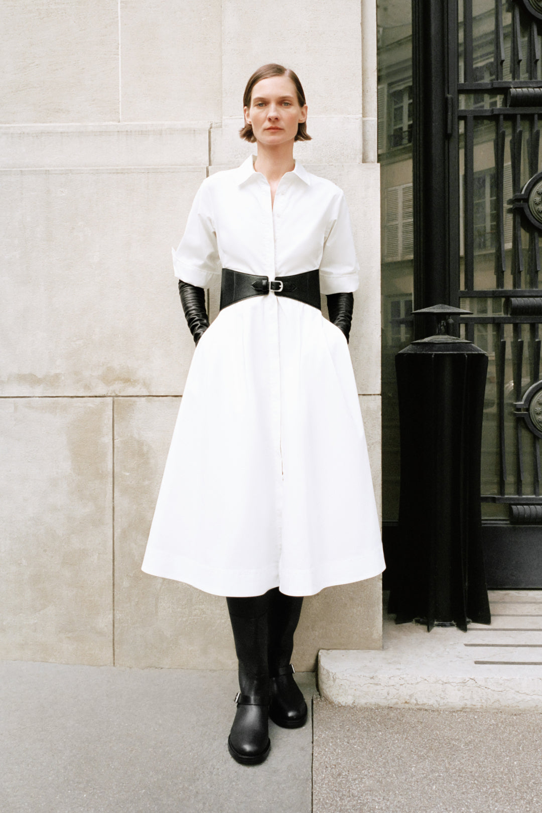 Woman wearing black leather over-the-knee boots with a white shirt and skirt.