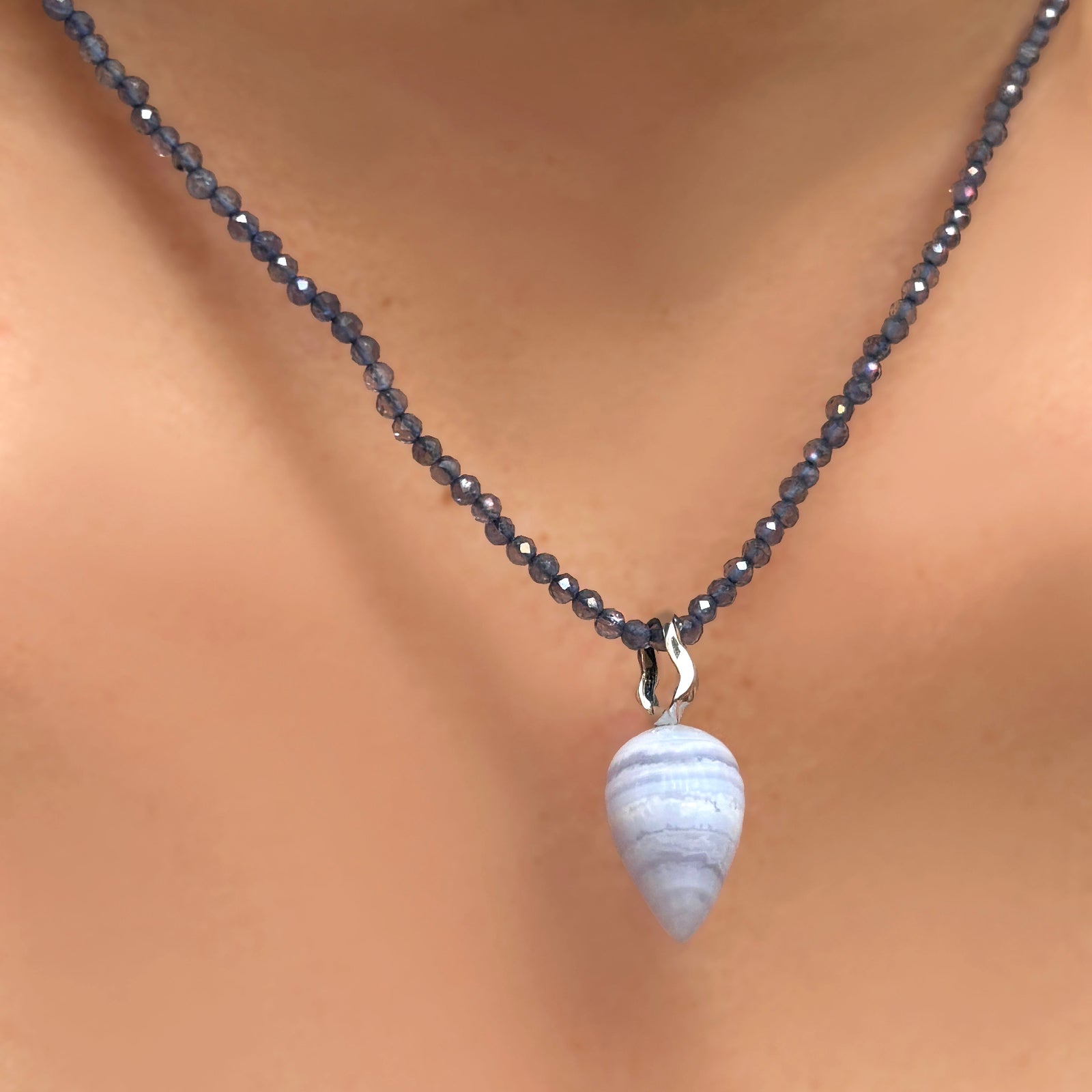 Iolite slim gemstone necklace with blue lace agate drop charm with ripple bale, on a model's neck.
