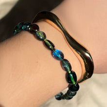 Molten Gold Cuff with blue green spinel on neon thread bracelet stacked on the wrist.
