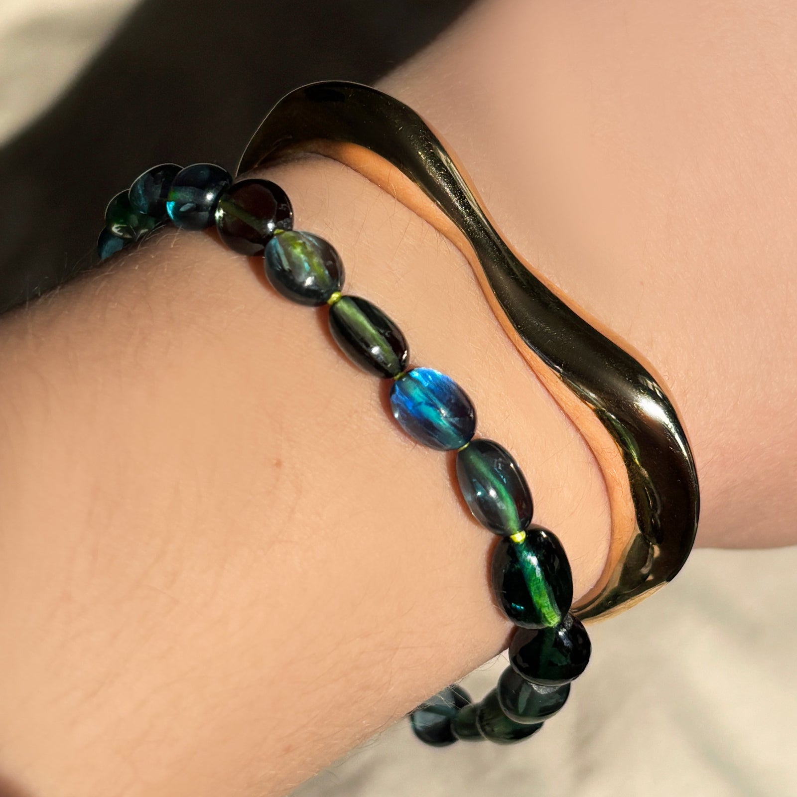 Molten Gold Cuff with blue green spinel on neon thread bracelet stacked on the wrist.