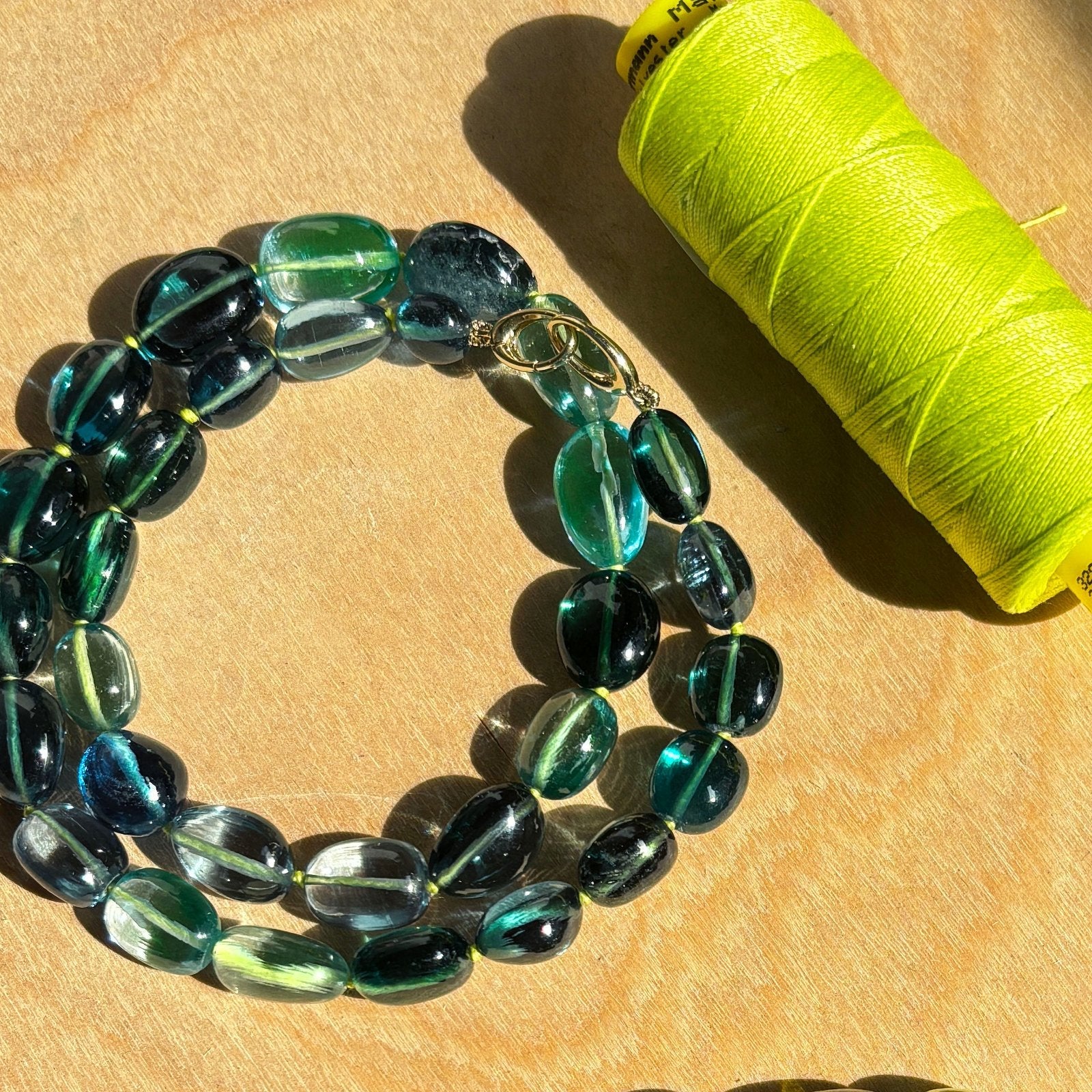 Shimmering beaded Green-Blue Spinel nugget bracelet with shades of green, blue on a surface.