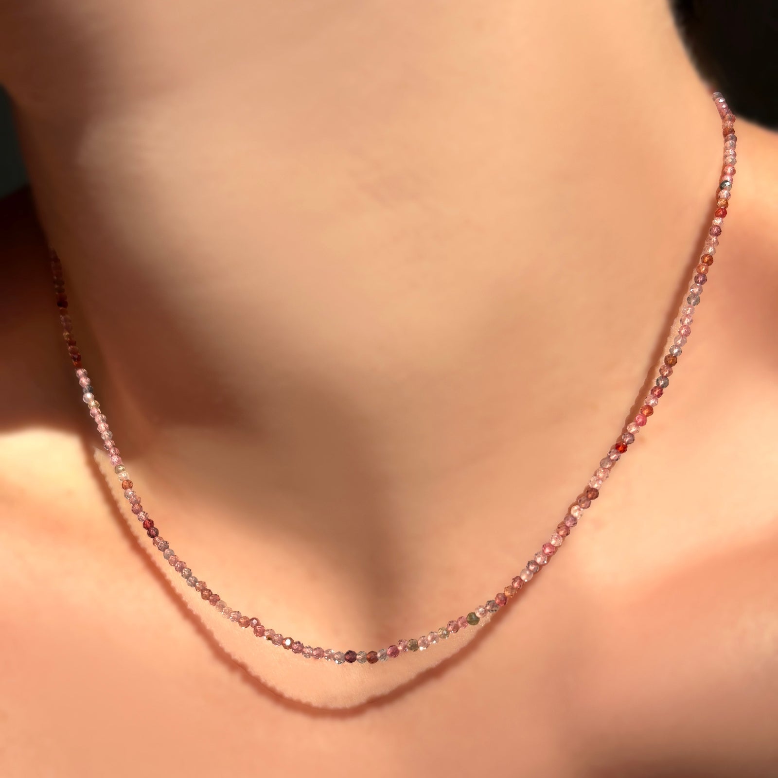 Red pink spinel slim gemstone necklace on a model's neck.